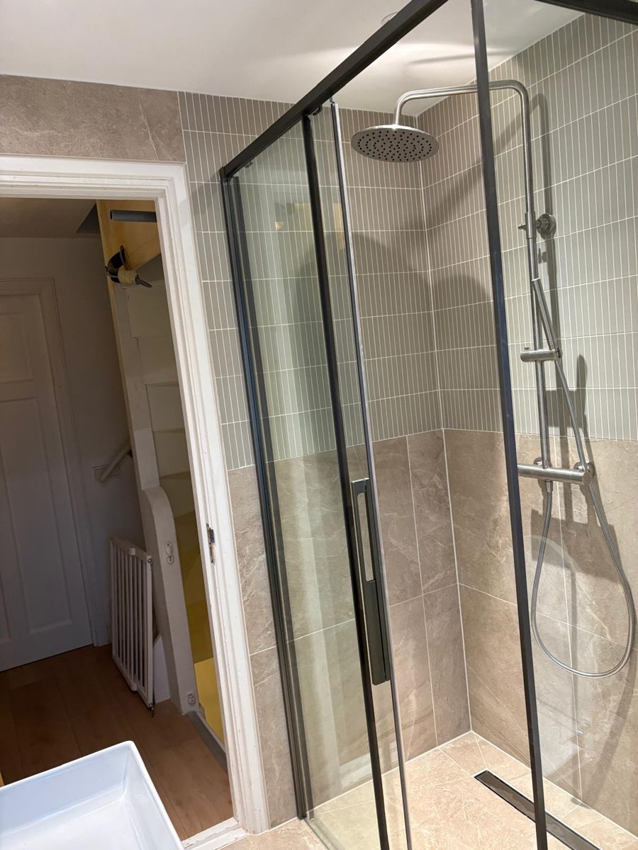 Nieuwe douche met glazen wand, regendouche en beige tegels