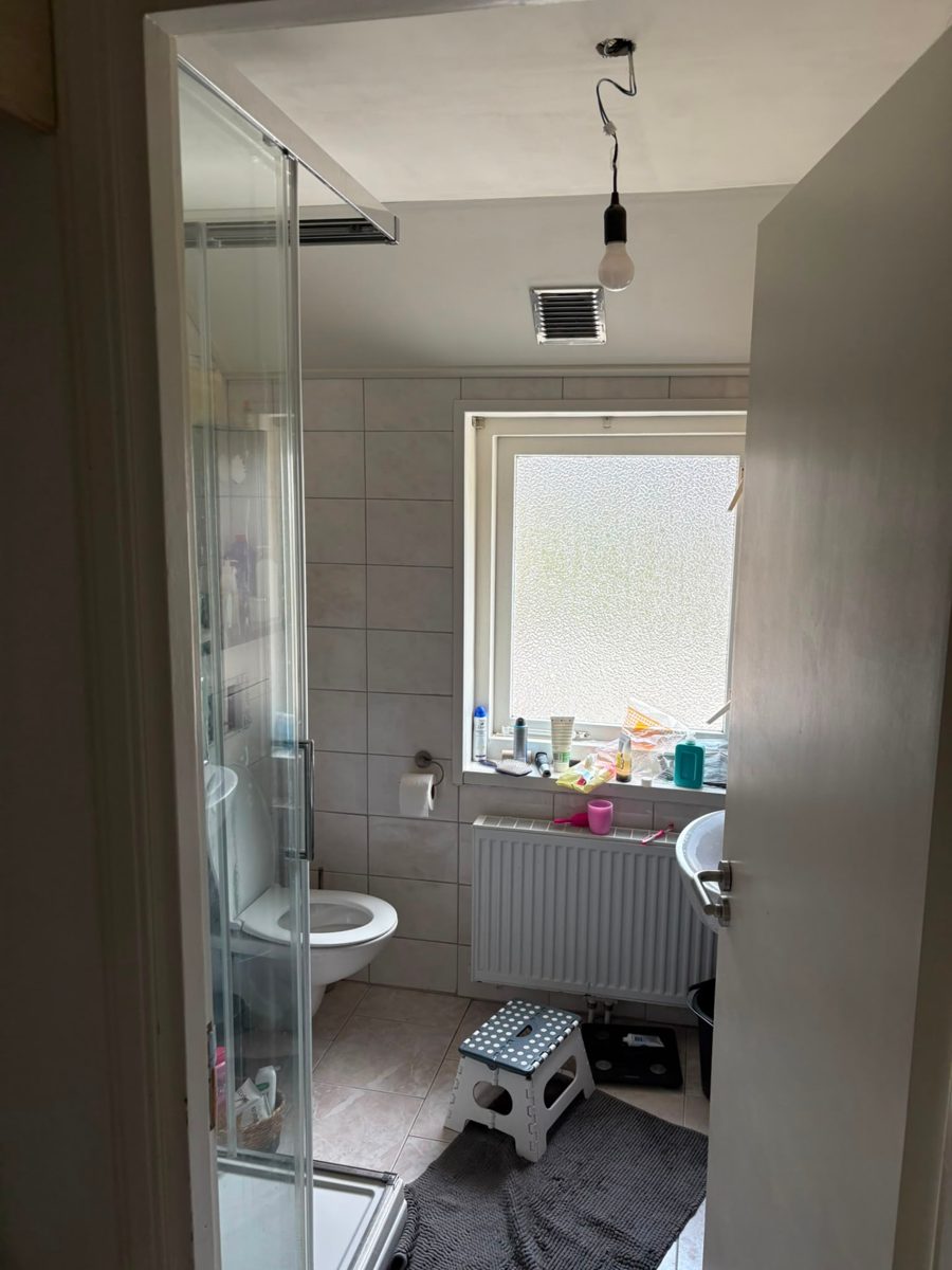 Badkamer voor de verbouwing: oude tegels, losse wastafel en klein raam